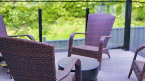 Korbstühle auf einer Terrasse mit Blick auf Grün.
