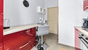 A compact kitchen with a red cabinet, a white countertop, a black clock, and a microwave. - Scarlatti31 - Beautiful apartment in the heart of Milan, Milan Central Station (Milano)