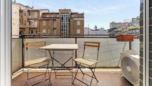 A balcony with a table and chairs, a fan, and a view of buildings. - Scarlatti31 - Beautiful apartment in the heart of Milan, Milan Central Station (Milano)