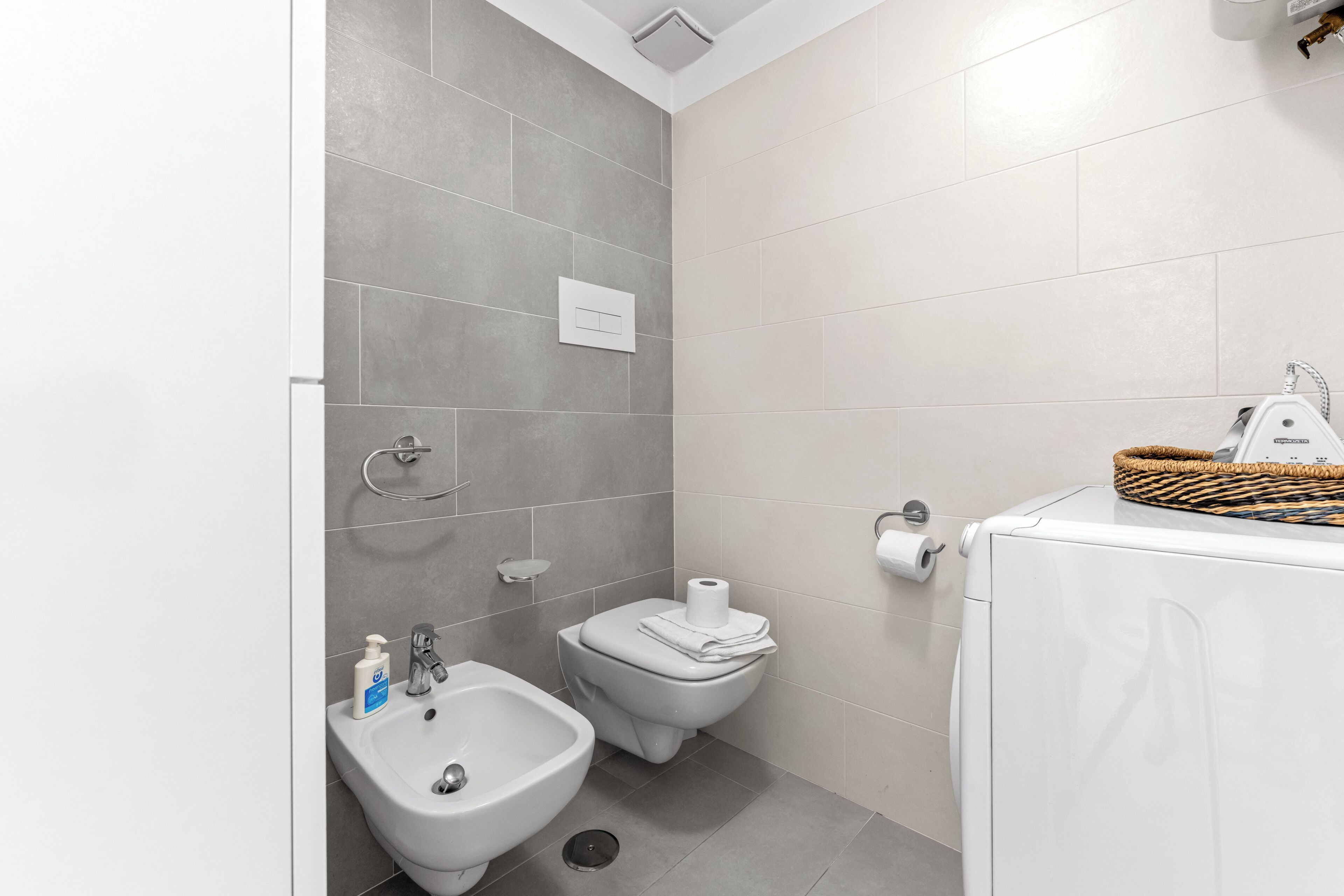 A modern bathroom with a bidet, toilet, and a washing machine.