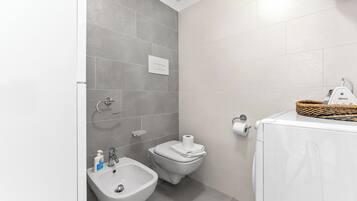 A modern bathroom with a bidet, toilet, and a washing machine.