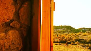 A stone wall adjacent to a wooden door leading to an outdoor landscape.