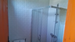 Une salle de bain comprenant des toilettes, un espace douche et un mur décoré d’un motif.