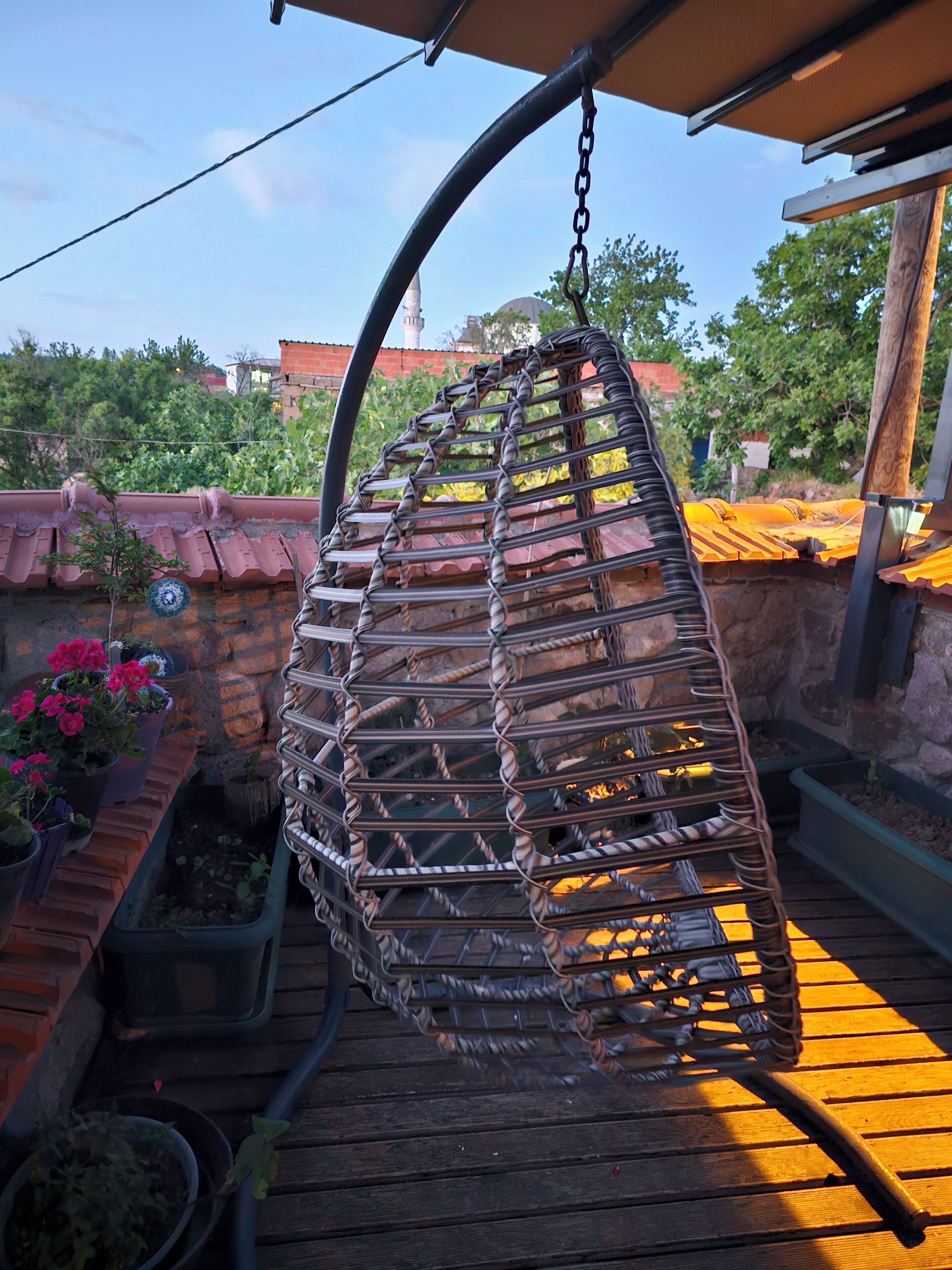 A hanging chair with a metal frame and a curved seat, suspended from a ceiling.