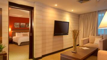 A hotel room with a bed, a TV mounted on the wall, a coffee table, and a sofa.