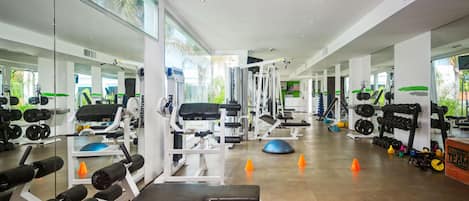 A modern gym with various exercise equipment, mirrors, and a clear view of the outdoors.