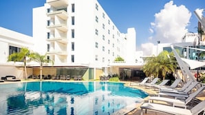 A hotel with a swimming pool, sun loungers, and a modern building with balconies. - Hotel Kristoff (Maracaibo)