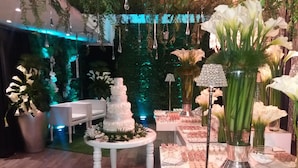 A wedding reception area with a tiered wedding cake, floral arrangements, and a variety of desserts on a table. - Hotel Kristoff (Maracaibo)