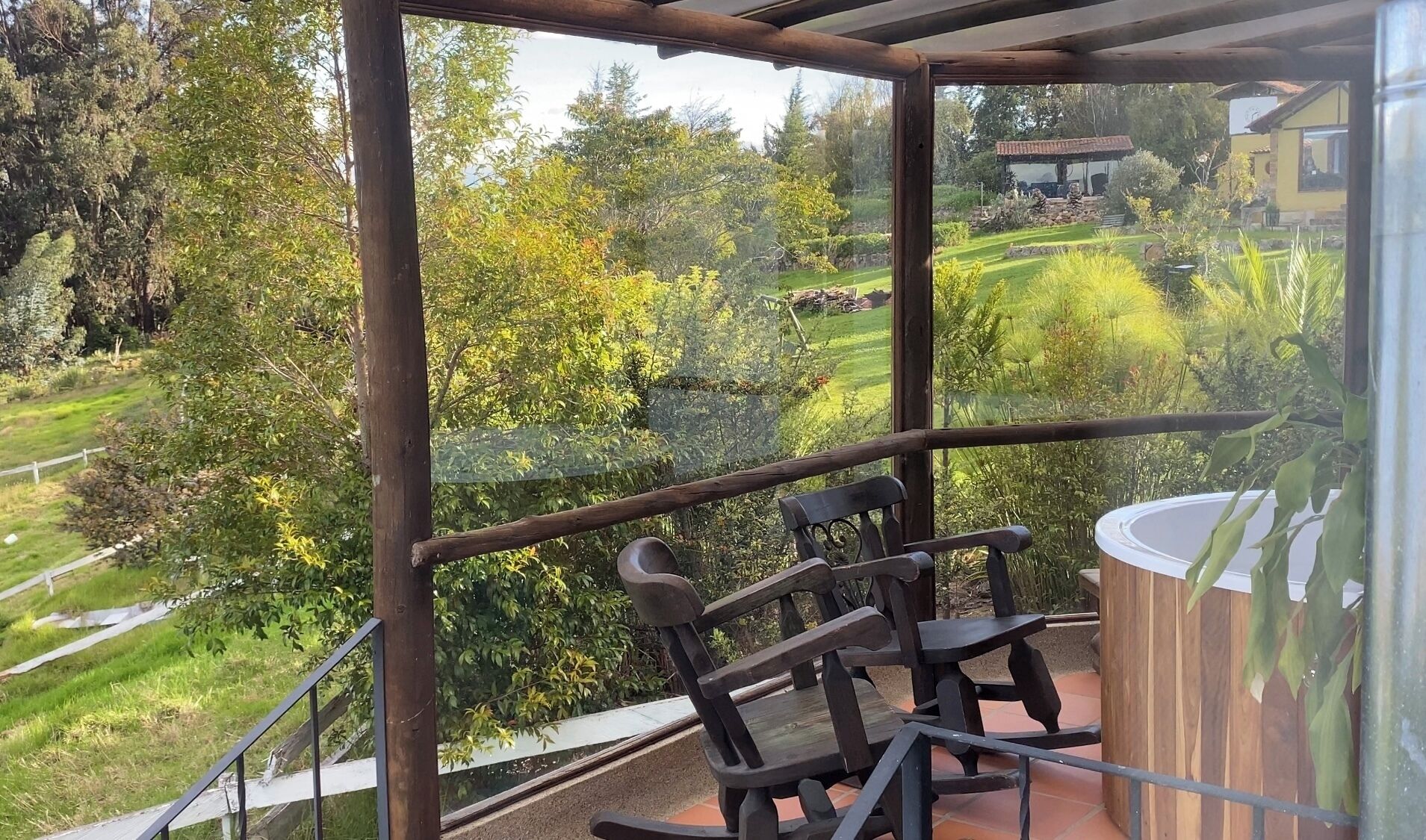 Un balcón con vista a un jardín y una casa al fondo.