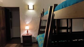 Habitación con literas, mesita de noche y lámpara.