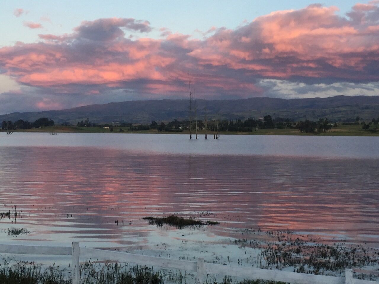 Ein See mit weiter Landschaft und bewölktem Himmel.