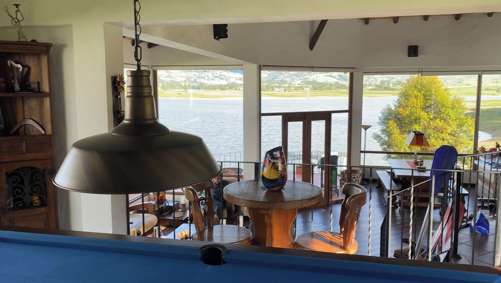 Un comedor con vista al lago, una mesa con sillas y una lámpara colgante.