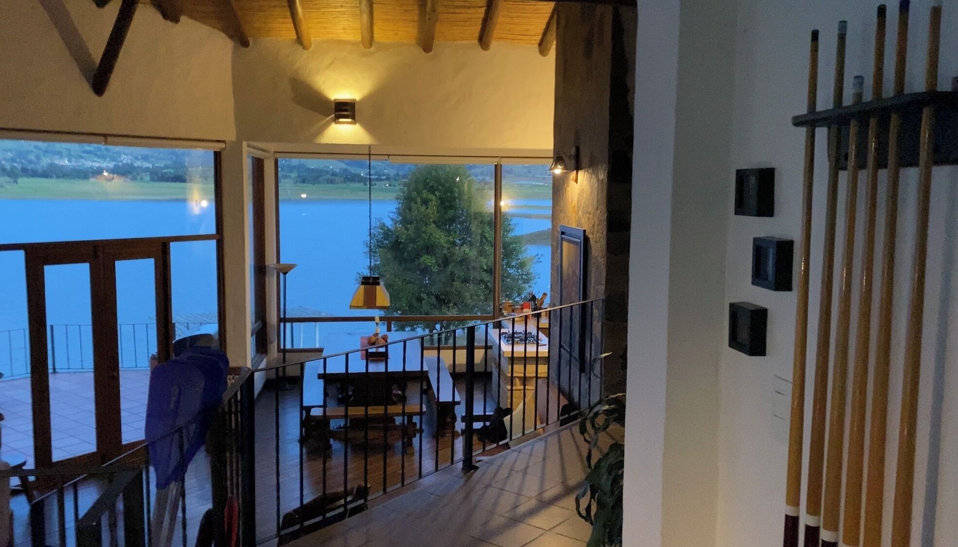 Un balcone con vista su un lago, un tavolo con sedie e una pianta pensile.