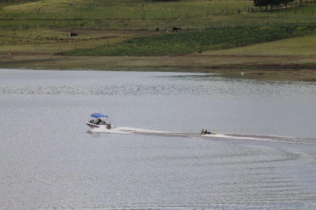 A body of water with a speedboat and a jet ski.