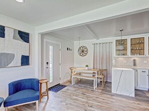 Ein geräumiges Wohnzimmer mit Esstisch, einem blauen Sofa und einer Küche mit Schränken und einer Marmor-Spritzschutzleiste.