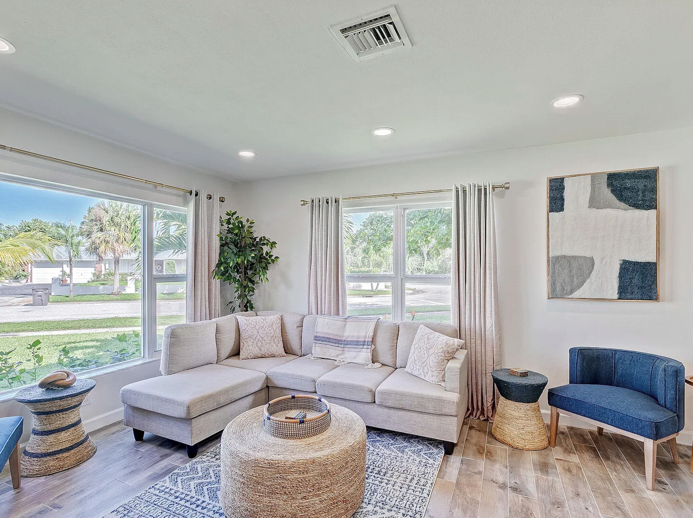A spacious living room with a large sectional sofa, a blue armchair, and a woven coffee table.