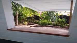 Um pequeno jardim cercado com um banco de madeira, várias plantas e pedras.