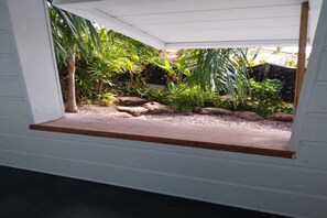 Ein kleiner, abgeschlossener Gartenbereich mit einer Holzbank, verschiedenen Pflanzen und Steinen.
