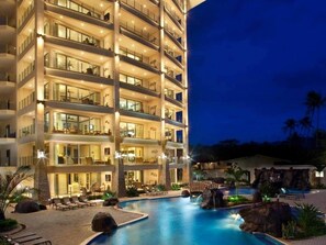A multi-story hotel with a swimming pool, outdoor seating, and a waterfall feature. - Diamante 701n - Downtown Jaco Deluxe Penthouse (Jaco)