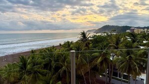 Blick auf einen Strand mit Palmen und einem bewölkten Himmel.