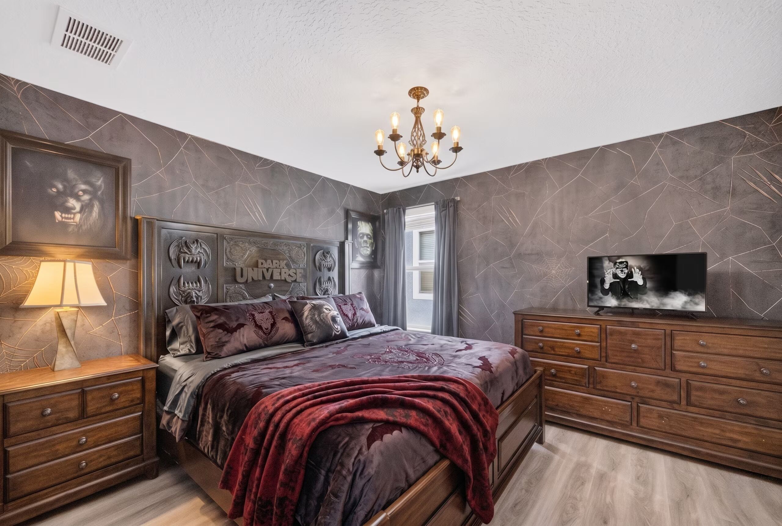 Ein Schlafzimmer mit Bett, Nachttischen, einem Fernseher und einer Chandelier.