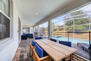 Un patio couvert avec une piscine, des sièges d’extérieur et une vue sur le paysage environnant.
