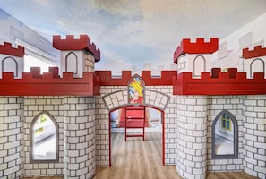 A castle-themed play area with brick walls, arched windows, and a central stained glass window. - The Epic Escape Mansion near Disney/Universal •Free Parking •5-Baths •25 Guests (Four Corners)