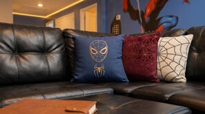 Ein Ledersofa mit drei Zierkissen mit Spinnennetz-Motiven.