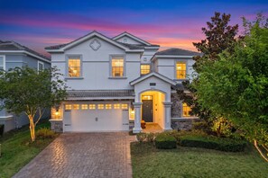 A two-story house with a garage, a driveway, and a well-maintained lawn. - The Epic Escape Mansion near Disney/Universal •Free Parking •5-Baths •25 Guests (Four Corners)