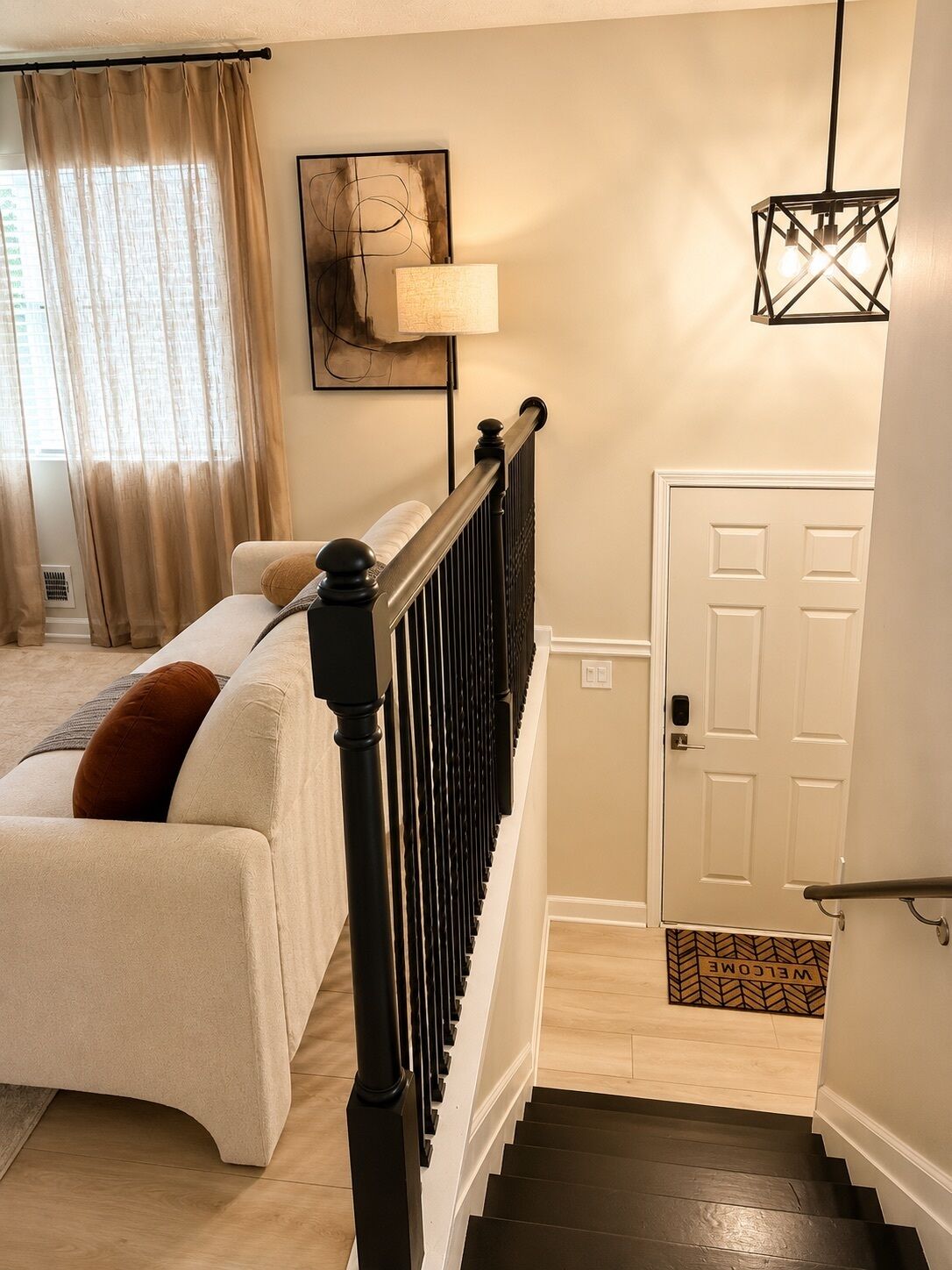 A bedroom with a bed, a nightstand, a lamp, a painting, a door, and a staircase.