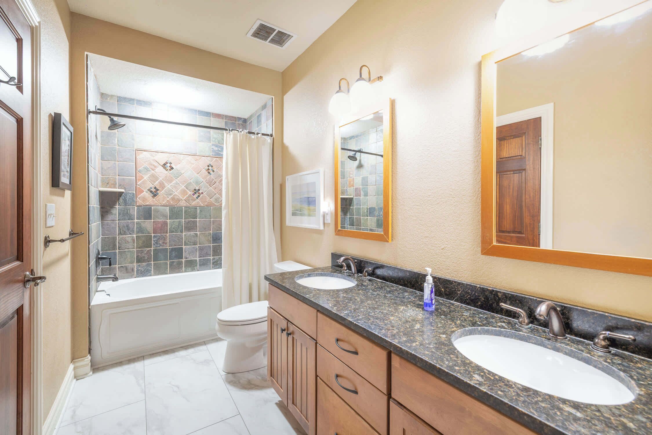 A bathroom with a bathtub, two sinks, and a shower.