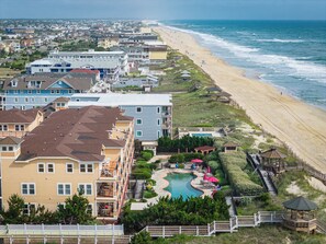 A coastal hotel with a beachfront view, a swimming pool, and a boardwalk.
