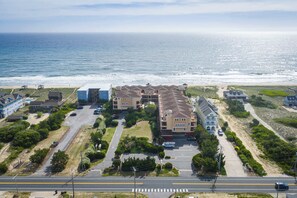 Un quartier résidentiel situé sur la côte, avec des maisons à plusieurs étages, une route principale et une plage en arrière-plan.