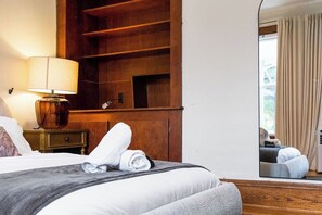 A hotel room with a bed, a nightstand with a lamp, a wooden wardrobe, and a view of the outdoors through a window. - Spacious 6-bedroom house in peaceful Fayetteville (Fayetteville)