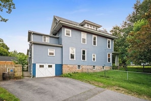 A two-story residential building with a garage, a stone foundation, and a fenced yard. - Spacious 6-bedroom house in peaceful Fayetteville (Fayetteville)