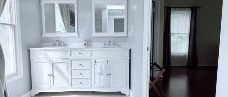A spacious bathroom with a large vanity, double sinks, and a walk-in shower.