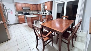 Une cuisine avec des meubles de rangement en bois, un îlot central et une table à manger avec des chaises.