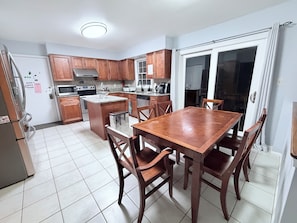 Una cocina con armarios de madera, una isla central y una mesa de comedor con sillas.