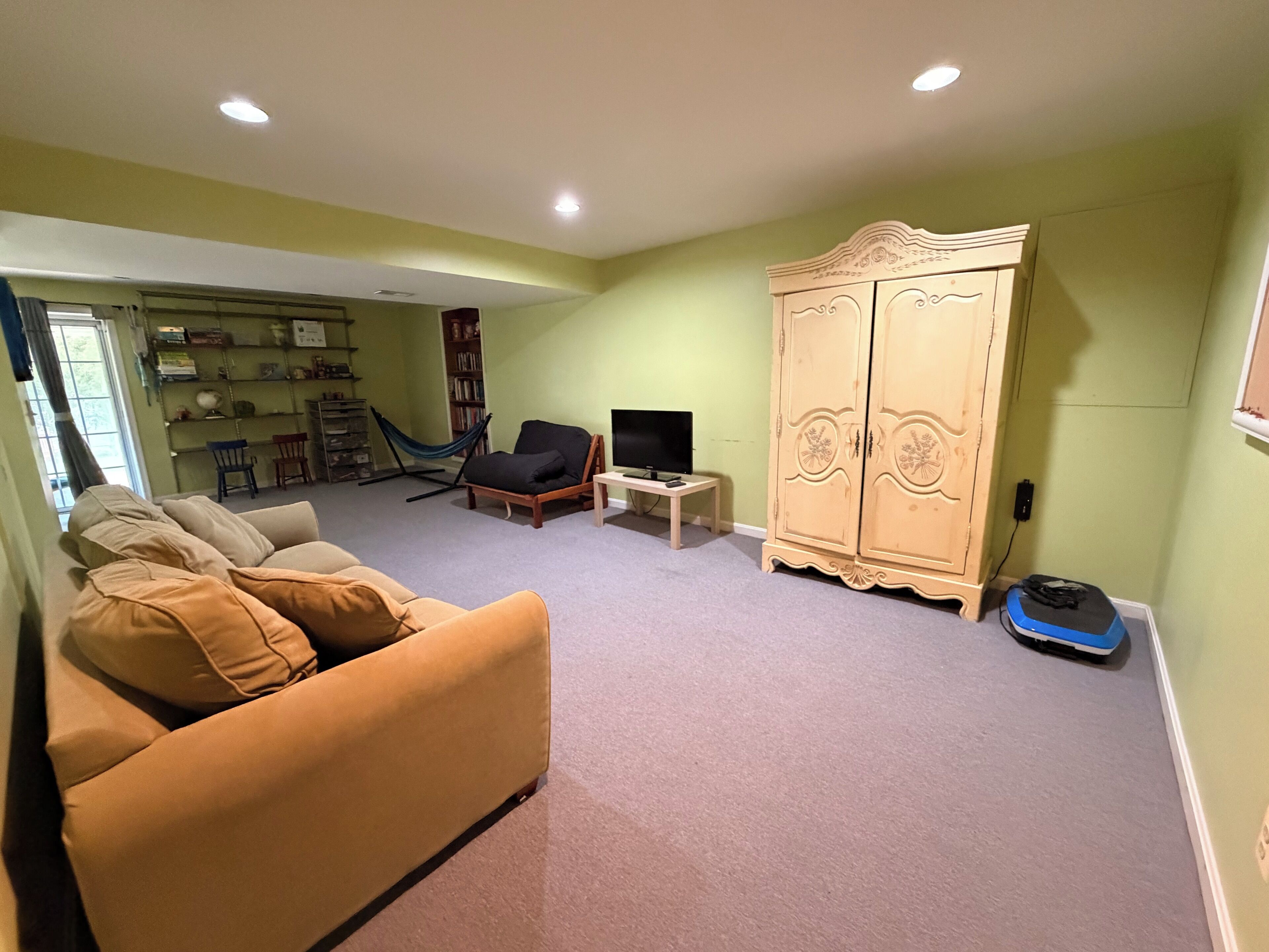 A living room with a sofa, a television, a bookshelf, and a wardrobe.