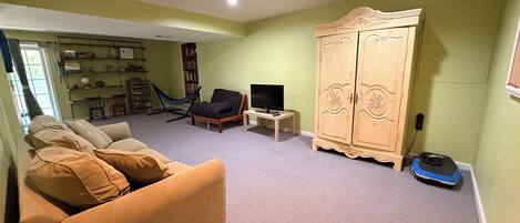 A living room with a sofa, a television, a bookshelf, and a wardrobe.