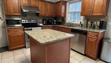 Una cocina con armarios de madera, una isla con encimera de granito, electrodomésticos de acero inoxidable y un ventanal.