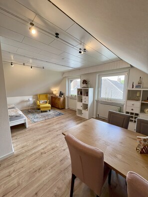 Een ruime slaapkamer op zolder, met een groot bed, een eettafel en een gezellige zithoek.