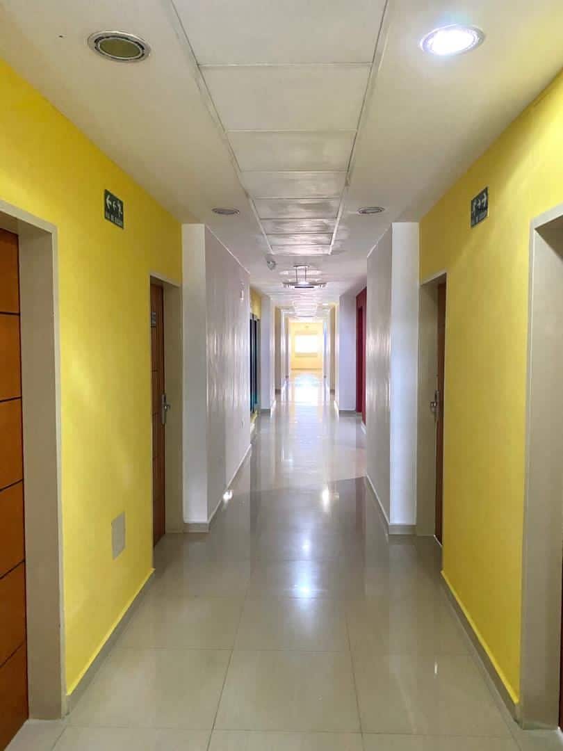 Um corredor longo e reto, com portas em ambos os lados, dando acesso a quartos.
