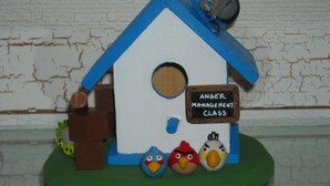 Uma casinha de pássaros com uma placa que diz 'ANGER MANAGEMENT CLASS'.
