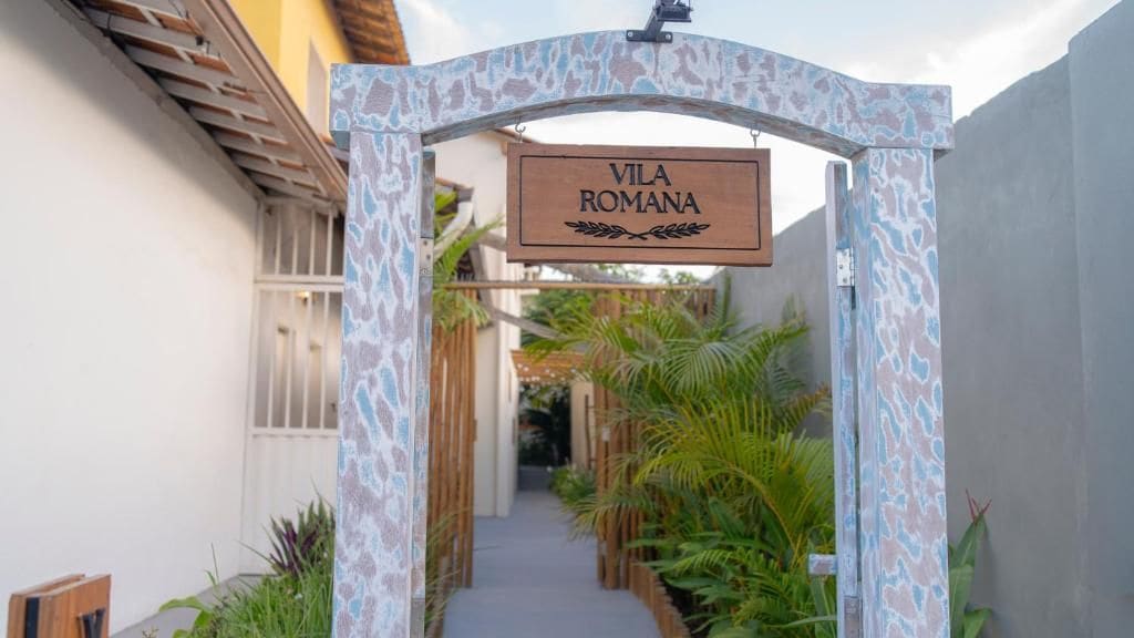 Uma placa de madeira com a inscrição 'VILA ROMANA', indicando o nome do local.