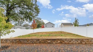 Un quartier résidentiel avec un mur de soutènement en pierre, une clôture blanche et des maisons en arrière-plan.
