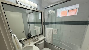 Ein Badezimmer mit einem großen Spiegel, einem Waschbecken, einer Toilette und einer Dusche.