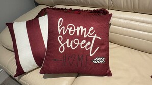 Ein Kissen mit dem Aufdruck 'home sweet home' auf einem beigen Sofa.