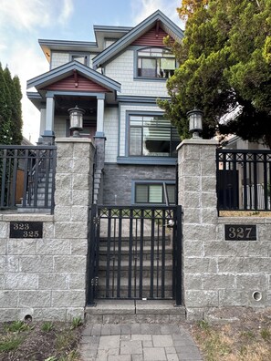 A two-story house with a stone facade, a black metal gate, and a number plaque. - 2BR Modern Suite - 20 mins to Downtown (Vancouver)