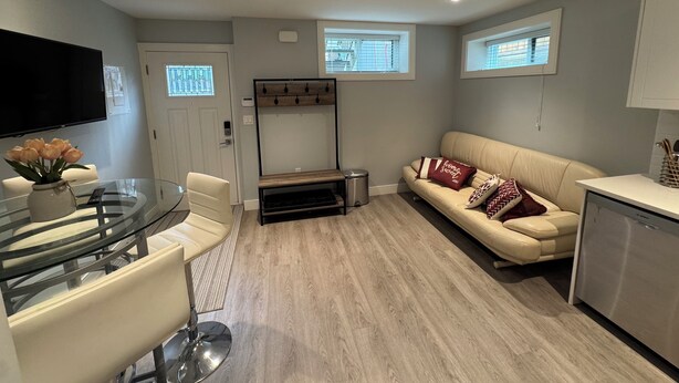 Ein modernes Wohnzimmer mit einem Glastisch, einem beigefarbenen Sofa und einem wandmontierten Flachbildfernseher.